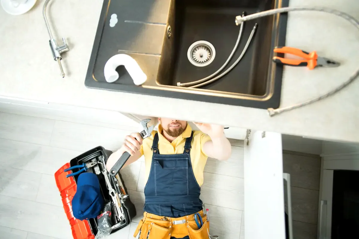 Fontanero desatascando una tubería de cocina con máquina eléctrica en Girona