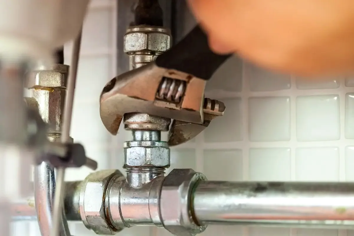 Fontanero comprobando una posible fuga de agua bajo un fregadero en Girona